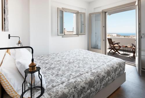 Un dormitorio blanco con una cama y un balcón. en Alchemy Villa - Prive Pool, en Megalokori