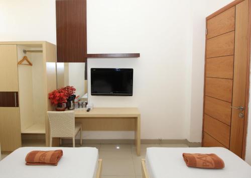 Habitación con escritorio y TV en la pared. en Ranez Inn, en Tegal