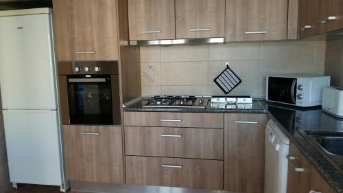 une cuisine avec des armoires en bois et un réfrigérateur blanc dans l'établissement Casa do carmo N 10, à Olhão