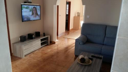 uma sala de estar com um sofá azul e uma televisão em Casa do carmo N 10 em Olhão