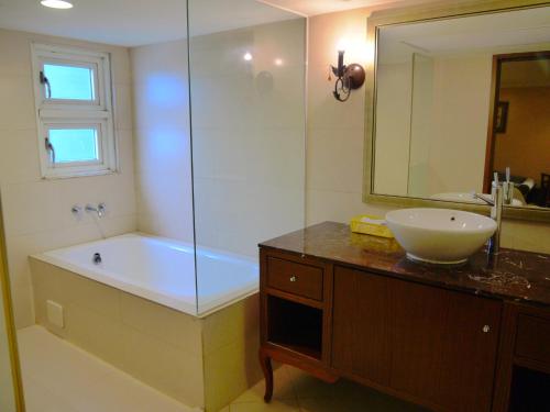 a bathroom with a tub and a sink and a mirror at Kai Wei Boutique Hotel in Taipei