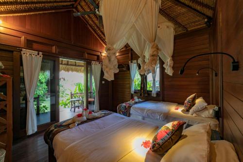 two beds in a room with wooden walls and windows at Ceningan Resort in Nusa Lembongan