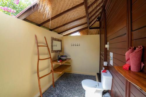 a bathroom with a toilet and a wooden ceiling at Ceningan Resort in Nusa Lembongan
