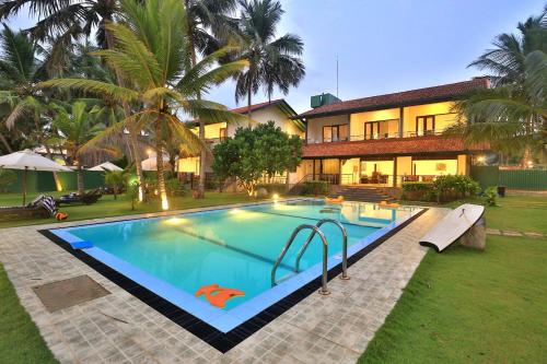 a swimming pool in front of a house at Sea Rock Villa in Bentota