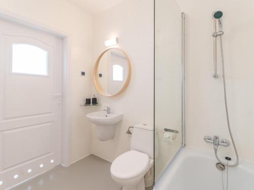 La salle de bains blanche est pourvue d'une douche et de toilettes. dans l'établissement Apartamenty Lighthouse - Jantar 20, à Kołobrzeg