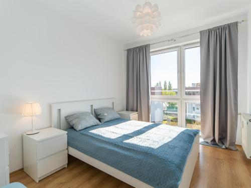 um quarto branco com uma cama e uma grande janela em Apartamenty Lighthouse - Jantar 20 em Kolobrzeg
