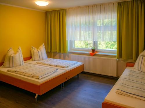 2 Betten in einem Zimmer mit gelben Wänden und einem Fenster in der Unterkunft Gästehaus am Oberlausitzer Dreieck in Bertsdorf