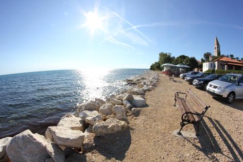 a bench on a beach next to the water at Villa Badi in Umag