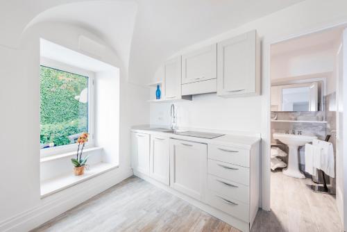 une cuisine blanche avec un évier et une fenêtre dans l'établissement Villa Dani, à Positano