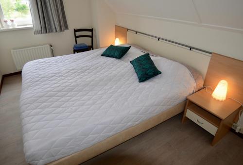 um quarto com uma grande cama branca e 2 almofadas verdes em Antibes 254 - Kustpark Village Scaldia em Hoofdplaat