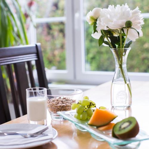 a table with a vase of flowers and a plate of fruit at Landhaus Pannonia in Mörbisch am See