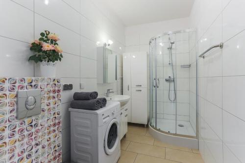 y baño blanco con ducha y lavadora. en Apartament Gdańsk z balkonem Stare Miasto en Gdansk