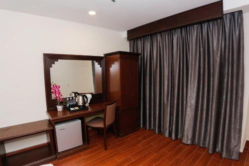 Zimmer mit einem Schreibtisch, einem Spiegel und einem Vorhang. in der Unterkunft Metro Hotel @ KL Sentral in Kuala Lumpur