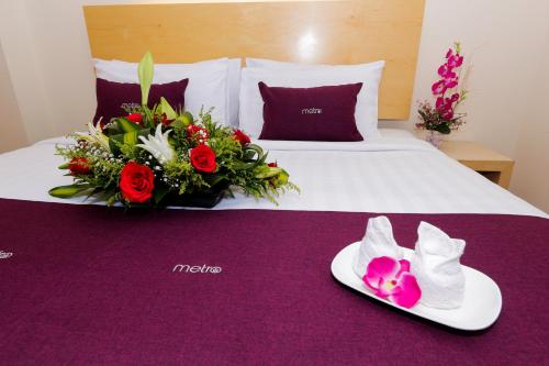 una habitación de hotel con una cama con zapatos y flores. en Metro Hotel @ KL Sentral en Kuala Lumpur