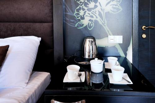 a table with cups and a tea pot on it next to a bed at Hotel Marsel in Tbilisi City