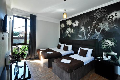 a bedroom with two beds and a large window at Hotel Marsel in Tbilisi City