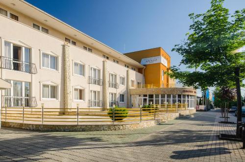 a building with a fence in front of a street at Hunguest Hotel Apollo in Hajdúszoboszló