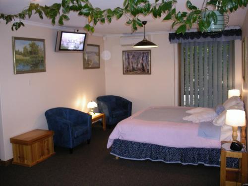 a bedroom with a bed and two blue chairs at Adelaide Hills B&B Accommodation in Stirling