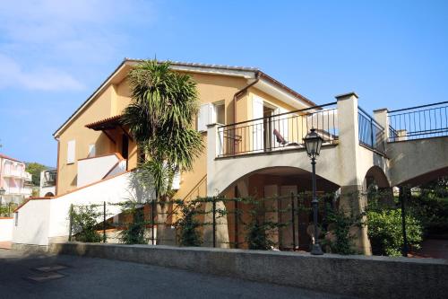 a house with a balcony and a palm tree at Residence La Meridiana in San Bartolomeo al Mare