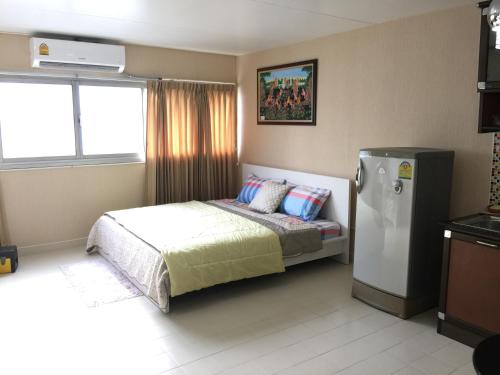 a bedroom with a bed and a refrigerator in it at Muangthongthani Rental/Khun Dan in Nonthaburi