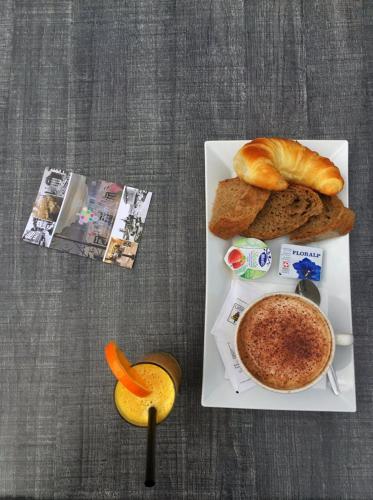 a plate of food with a cup of coffee and bread at Hôtel du Raisin in Lausanne