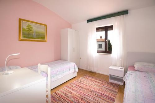 a bedroom with two beds and a desk and a window at Apartman sa tri spavaće sobe u blizini plaže in Premantura