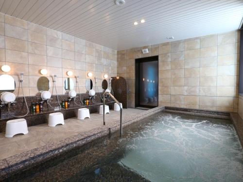 La salle de bains est pourvue d'une piscine d'eau avec des lavabos et des miroirs. dans l'établissement Hotel Wing International Select Higashi Osaka, à Osaka