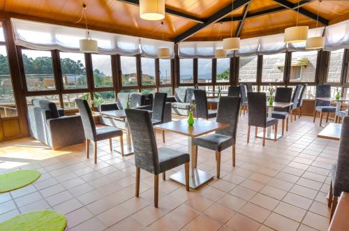 a restaurant with tables and chairs and windows at Hotel & Apartamentos Cons da Garda in San Vicente de O Grove