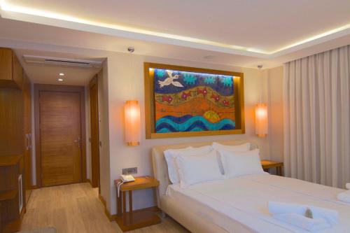 a bedroom with a white bed and a painting on the wall at Marisol Boutique Hotel in Gundogan