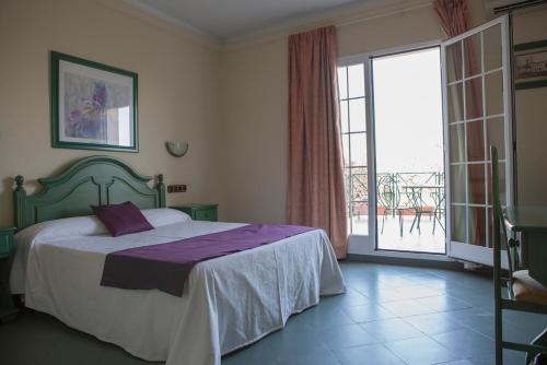 a bedroom with a bed and a large window at Hotel Mitra Crisálida in Cabra