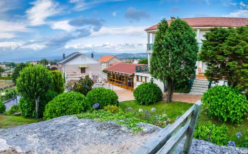a house with a garden and a fence at Hotel & Apartamentos Cons da Garda in San Vicente de O Grove