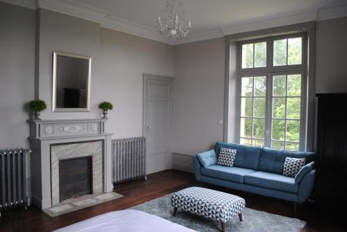 a living room with a blue couch and a fireplace at Chateau Mezger in Albefeuille-Lagarde