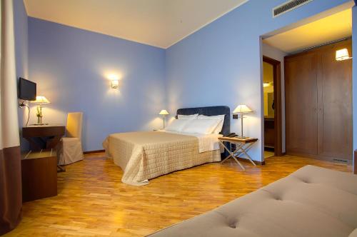 um quarto com uma cama, uma mesa e uma televisão em Hotel Messenion em Messina