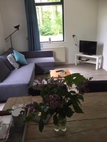 een woonkamer met een bank en een tafel met bloemen bij Speldehof in Kraggenburg