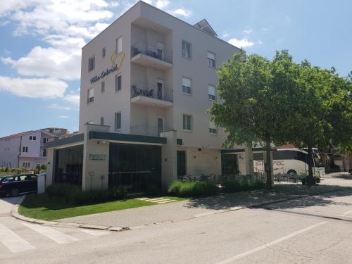 a tall white building with a tree in front of it at Villa Gabriel in Međugorje