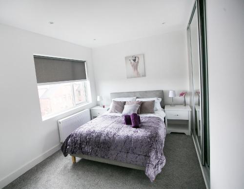 a bedroom with a bed with a purple blanket at Queens Quarter Apartments in Belfast