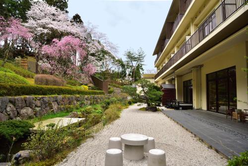 una pasarela junto a un edificio con flores rosas en Kyo Yunohana Resort Suisen en Kameoka