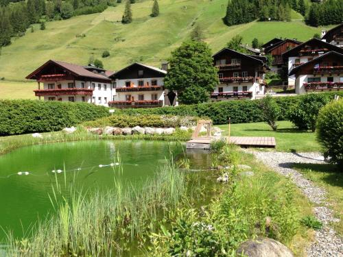 un complexe avec un étang et des maisons sur une colline dans l'établissement Ferienappartements Heinzle - Ihr Ferienresort, à Sankt Jakob in Defereggen