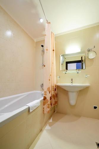a bathroom with a tub and a sink and a bath tub at Penelopa Palace Apart Hotel & SPA in Pomorie