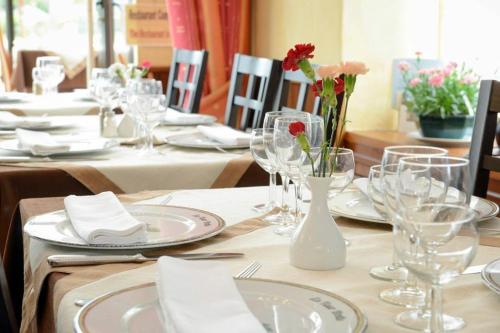 una mesa con vasos, platos y flores. en Logis Hôtel et Restaurant La Tour Brette, en Pontorson