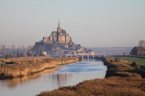 a castle on a hill next to a river at Logis Hôtel et Restaurant La Tour Brette in Pontorson