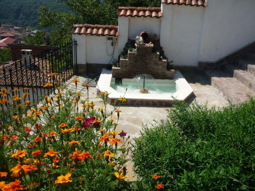 a fountain in the middle of a garden with flowers at Guest House Harmony in Veliko Tŭrnovo
