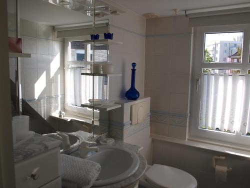 ein Bad mit einem Waschbecken, einem WC und einem Fenster in der Unterkunft Haus am Meer in Cuxhaven