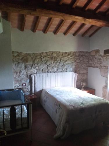 1 dormitorio con 1 cama en una pared de piedra en Appartamento Azzurra en Roccalbegna