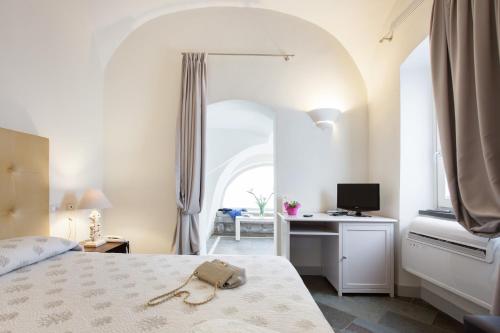 a bedroom with a bed and a desk with a computer at Hotel Maison Tresnuraghes in Tresnuraghes