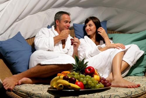 a man and woman sitting on a couch with a plate of fruit at Hotel Praha in Špindlerův Mlýn