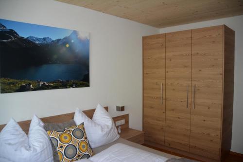 1 dormitorio con 1 cama y armario de madera en Apart Geiger, en Arzl im Pitztal