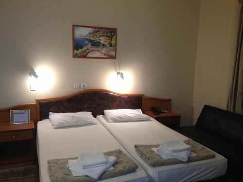 two beds in a hotel room with towels on them at Sappho Hotel in Skala Eresou