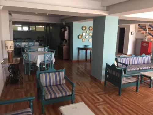 a dining room with chairs and tables and a room with blue walls at Knossos Hotel in Tolo