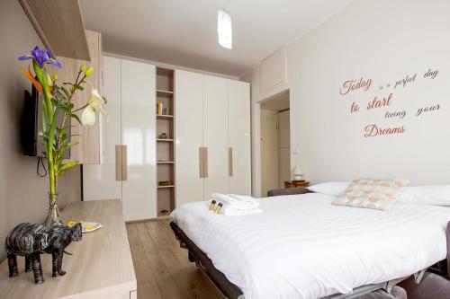 1 dormitorio con 1 cama grande y un jarrón con flores en Lorenteggio Studio Apt, en Milán